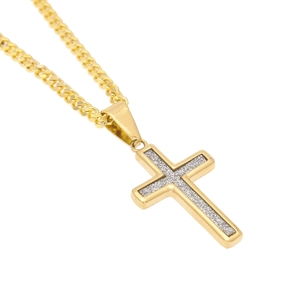 Détail d'un pendentif croix dorée avec incrustation argentée sur chaîne gourmette