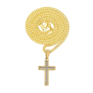 Détail du pendentif croix dorée avec paillettes argentées sur une chaîne gourmette