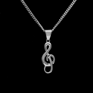 Détail macro d'un pendentif clé de sol en acier inoxydable poli sur sa fine chaîne
