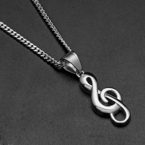 Vue macro du pendentif clé de sol poli et de la chaîne cubaine sur un fond texturé noir
