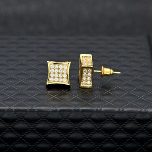 Gros plan de boucles d'oreilles carrées dorées pavées de zircons sur fond texturé noir