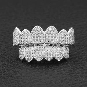 Macro shot of silver hip-hop grillz with pavé zircon stones and sharp fangs on black leather