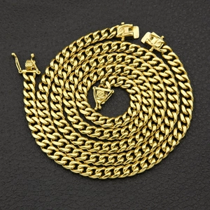 Macro view of gold Cuban link chain necklace with secure clasp on black background