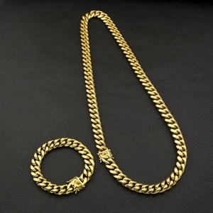 Close-up of gold Cuban link chain set showing the secure clasp on black leather background