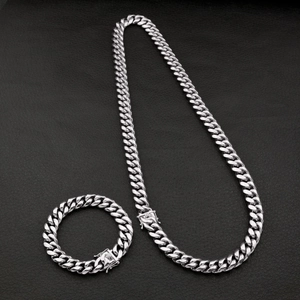 Detail of silver Cuban link chain set with engraved geometric textures on the clasp