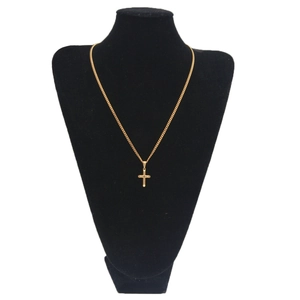 Gros plan d'un pendentif croix dorée et d'une chaîne fine sur un buste de bijoutier noir