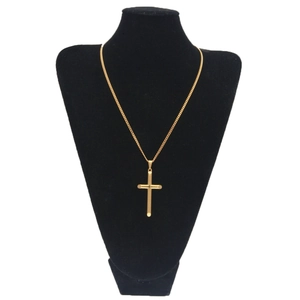 Détail d'un pendentif croix en or poli avec des lignes gravées sur un buste noir
