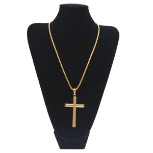 Gros plan d'un pendentif croix doré sur une chaîne à mailles carrées épaisses