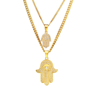 Macro detail of gold plated Hamsa Hand necklaces with shiny diamond-set pendants