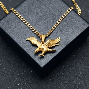 Dettaglio del ciondolo a forma di aquila placcato oro con piume incise su catena cubana