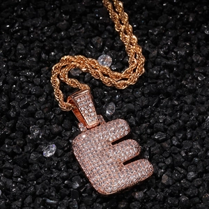 Vue rapprochée du pendentif hip hop lettre E en or rose avec zircons blancs et chaîne corde
