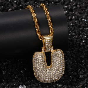 Détail du pendentif hip-hop lettre U serti de zircons blancs sur chaîne dorée