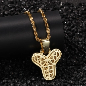 Vue macro du pendentif épée hip-hop doré avec dos texturé et chaîne de type corde