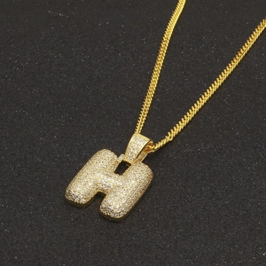 Gros plan du pendentif lettre H plaqué or avec zircons sur une chaîne cubaine