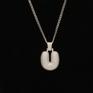 Vue macro d'un pendentif lettre U argenté avec zircons pavés sur une chaîne à maillons