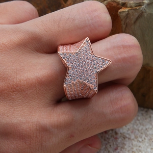 Détail d'une bague étoile hip-hop en or rose avec sertissage de cristaux scintillants