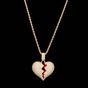 Dettaglio del ciondolo a cuore spezzato dorato con zirconi e smalto rosso su catena a corda