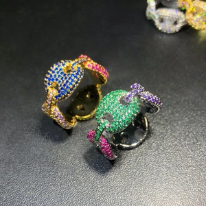 Macro view of iced-out hip hop rings with colorful zircon stones on black background