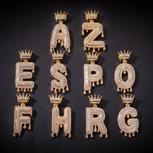 Detail von goldenen Hip-Hop-Anhängern mit Tropfenbuchstaben, Kronen und weißen Zirkonia