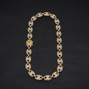 Detailed macro shot of a gold coffee bean link chain with white crystals on a black background