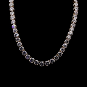 Gros plan d'un collier tennis doré avec zircons ronds sertis à 4 griffes sur fond noir pur