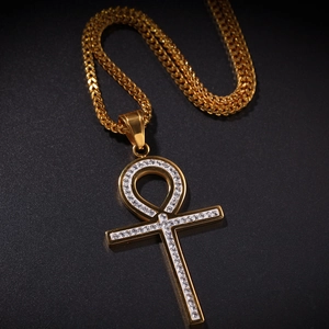 Détail macro du pendentif croix Ankh doré serti de zircons avec chaîne épi épaisse