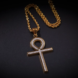 Gros plan détaillé du pendentif croix Ankh en or avec zircons et sa chaîne de style corde