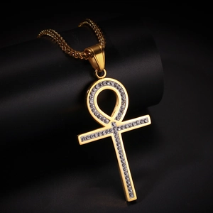 Gros plan du pendentif croix Ankh doré serti de strass blancs et chaîne torsadée