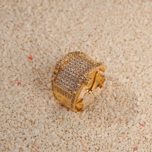 Hip hop gold plated ring with paved zircons on sand background for men and women