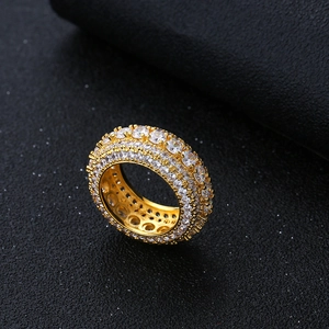 Dettaglio anello hip hop dorato con pavé di zirconi cubici su sfondo in pelle