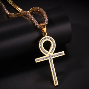 Gros plan du pendentif croix Ankh doré serti de zircons avec une chaîne tennis noire