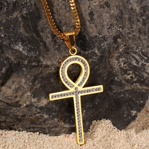 Gros plan du pendentif Ankh doré avec cristaux blancs sur un fond de roche grise