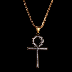 Gros plan détaillé du pendentif croix Ankh doré avec strass blancs sur fond noir