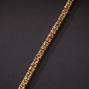 Macro shot of 2mm gold tennis bracelet chain with a polished metallic mirror finish