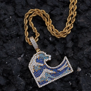 Macro detail of Great Wave pendant with blue and white zircons on a gold rope chain