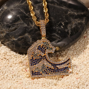 Macro shot of gold hip hop pendant with blue white zircon wave on black rock and sand