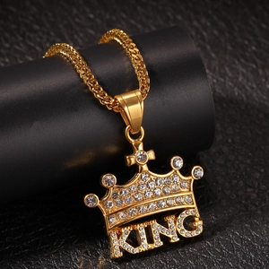 Close-up of golden crown pendant with KING letters and sparkling white rhinestones on chain