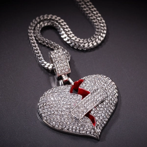 Dettaglio del ciondolo cuore spezzato con brillantini e cerotto su catena cubana spessa