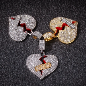 Dettaglio di ciondoli a cuore spezzato con strass e cerotto decorativo su fondo in pelle nera
