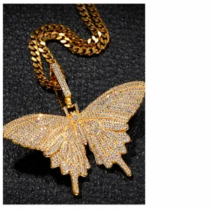 Detail van hiphop vlinder hanger met witte zirkoon op een gouden Cubaanse ketting