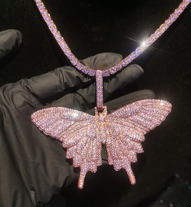 Detail van de vlinderhanger met roze zirkonia en roségouden tennisketting in hiphop-stijl