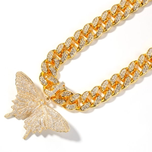 Macro-opname van gouden Cubaanse ketting en vlinderhanger met glanzende zirkonia's