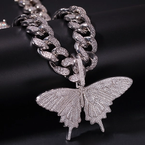 Macro-opname van een zilveren iced out Cubaanse ketting met een fonkelende vlinderhanger
