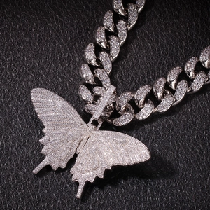 Detailopname van de zilveren cubaanse schakelketting met ijzige vlinder hanger op leer