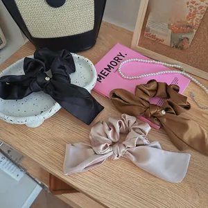 Dettaglio di elastici scrunchie in raso con nastri lunghi in nero, caffè e champagne