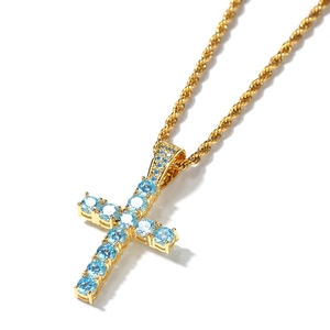 Dettaglio del ciondolo a croce con zirconi blu cielo su una catena a corda dorata