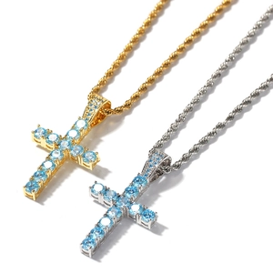 Dettaglio macro dei ciondoli a croce in oro e argento con zirconi blu su catene a corda