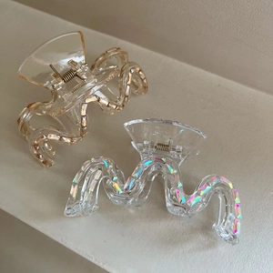 Détail de pinces à cheveux ondulées pailletées en tons champagne et transparents à strass