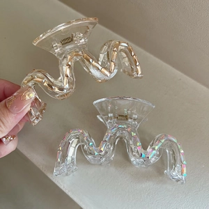 Détail de deux grandes pinces à cheveux ondulées en ambre et blanc avec des paillettes