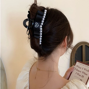 Grosse pince à cheveux noire avec nœud en satin et perles blanches sur modèle
